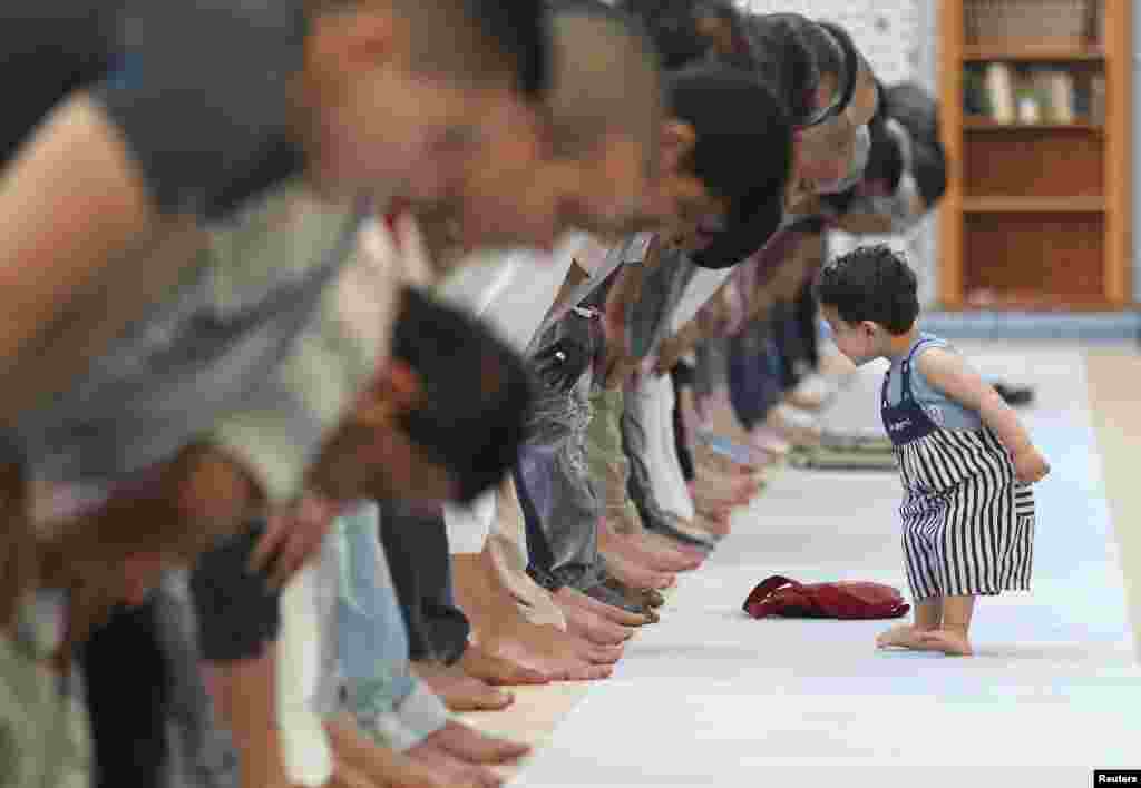 Seorang anak kecil berjalan di dekat para jamaah Muslim yang sedang melaksanakan sholat Dzuhur berjamaah di Masjid Agung di kota Strasbourg, Perancis, pada hari pertama bulan Ramadan.