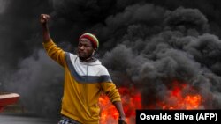 Um manifestante em frente a pneus queimados na manifestação contra o governo em Luanda, 24 Outubro 2020