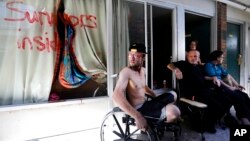 Wes Allen Jr., from left, sits with his father, Wes, his sister, Alison and his mother, Vicki, outside their room at a damaged motel, Oct. 16, 2018, in Panama City, Fla., where many residents continue to live in the aftermath of Hurricane Michael. Many residents rode out the storm and have no place to go, even though many of the motel's rooms are uninhabitable.