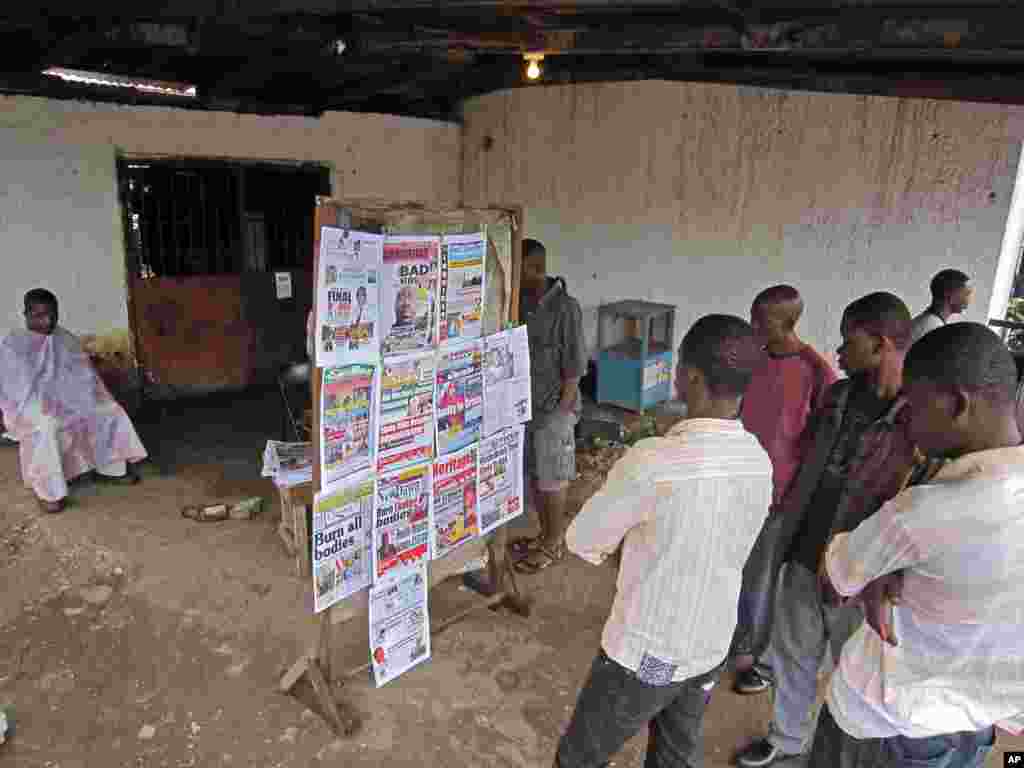 A group of people read the headlines of a newspaper that reads 'Burn all bodies' in the city of Monrovia, Liberia, July 31, 2014.