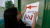 FILE - Ailu Xu, a graduate student from China, posts a sign directing Chinese students to new student orientation at the University of Texas at Dallas in Richardson, Texas, Aug. 22, 2015. 