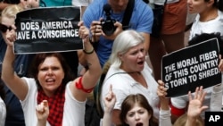 Para perempuan mengacungkan spanduk pada saat berunjuk rasa memprotes pemisahan keluarga imigran ilegal, di luar Gedung Kantor Senat di Washington DC, 28 Juni 2018.
