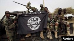 Soldados del ejército de Nigeria sostienen una bandera del grupo armado Boko Haram, después de los operativos contra los extremistas.