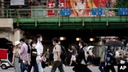 People wearing protective face masks to help curb the spread of the coronavirus walk at a pedestrian crossing in Tokyo, July 10, 2020.