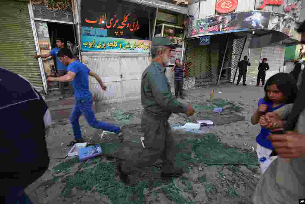 A member of the Afghan security forces walks over broken glass after a suicide car bombing attack in Kabul, May 19, 2015.