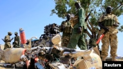 South Sudan army soldiers stand next to a destroyed motorcycle near Bor Airport, northwest of capital Juba on December 25, 2013. 