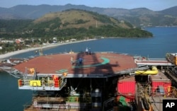 FILE - Petrobras workers walk on platform 51 "Majuro" in Angra dos Reis, Brazil, Aug. 21, 2008. (AP Photo/Ricardo Moraes, File)