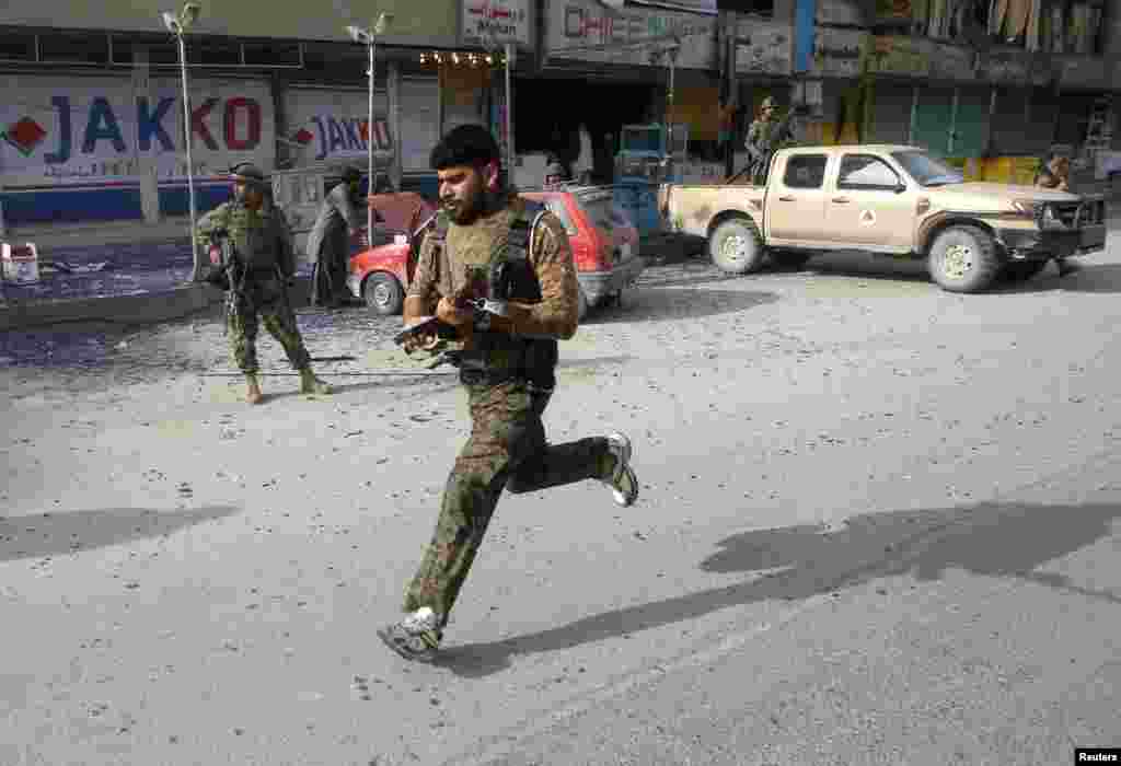 Afghan security forces run in the aftermath of a suicide car bomb attack in Jalalabad province, Afghanistan, March 20, 2014.