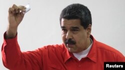 Venezuelan President Nicolas Maduro show his ballot as casts his vote at a polling station during the Constituent Assembly election in Caracas, Venezuela, July 30, 2017. 