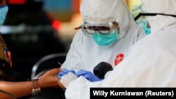 Ilustrasi. Petugas kesehatan yang mengenakan alat pelindung mengambil sampel darah untuk menguji seorang pria terhadap virus corona (COVID-19) di Bogor, Jawa Barat, 7 April 2020. (Foto: Reuters/Willy Kurniawan)