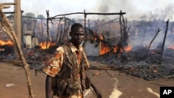 A policeman walks past the smouldering remains of a market in Rubkona near Bentiu in South Sudan, April 23, 2012.