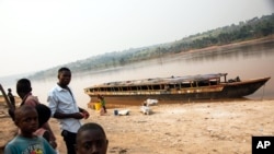 Quelques personnes à côté d'un bateau vide, sur le bord de la rivière Kasaï, au port de Tshikapa, en République démocratique du Congo, le 28 juillet 2017. 