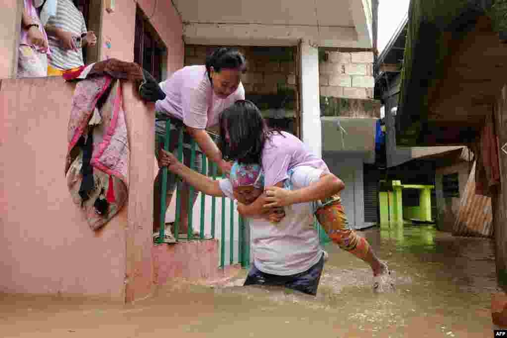 Residents evacuate from their flooded homes due to a swollen river caused by heavy rains and induced by Super Typhoon Man-yi in Tuguegarao City, Cagayan province. Floodwaters submerged houses and highways in the northern Philippines after water released from a dam following Typhoon Man-yi caused a major river to break its banks.