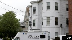 Police vehicles sit in front of a multistoried home in Everett, Mass., being searched by authorities in connection with the fatal police shooting of a man earlier in the day in Boston, June 2, 2015.