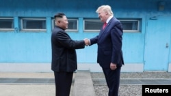FILE - Then-U.S. President Donald Trump shakes hands with North Korean leader Kim Jong Un as they meet at the demilitarized zone separating the two Koreas, in Panmunjom, South Korea, June 30, 2019.