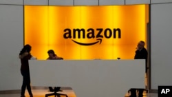 In this Feb. 14, 2019 file photo, people stand in the lobby for Amazon offices in New York. 