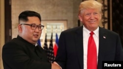Arhiv - Kim Jong Un se rukuje sa Donaldom Trumpom za vrijeme samita u Singapuru, 12. juni 2018.