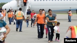 Women and children walk on the tarmac after being deported from the U.S., at the Ramon Villeda international airport in San Pedro Sula, in this July 14, 2014 handout provided by the Honduran Presidential House.