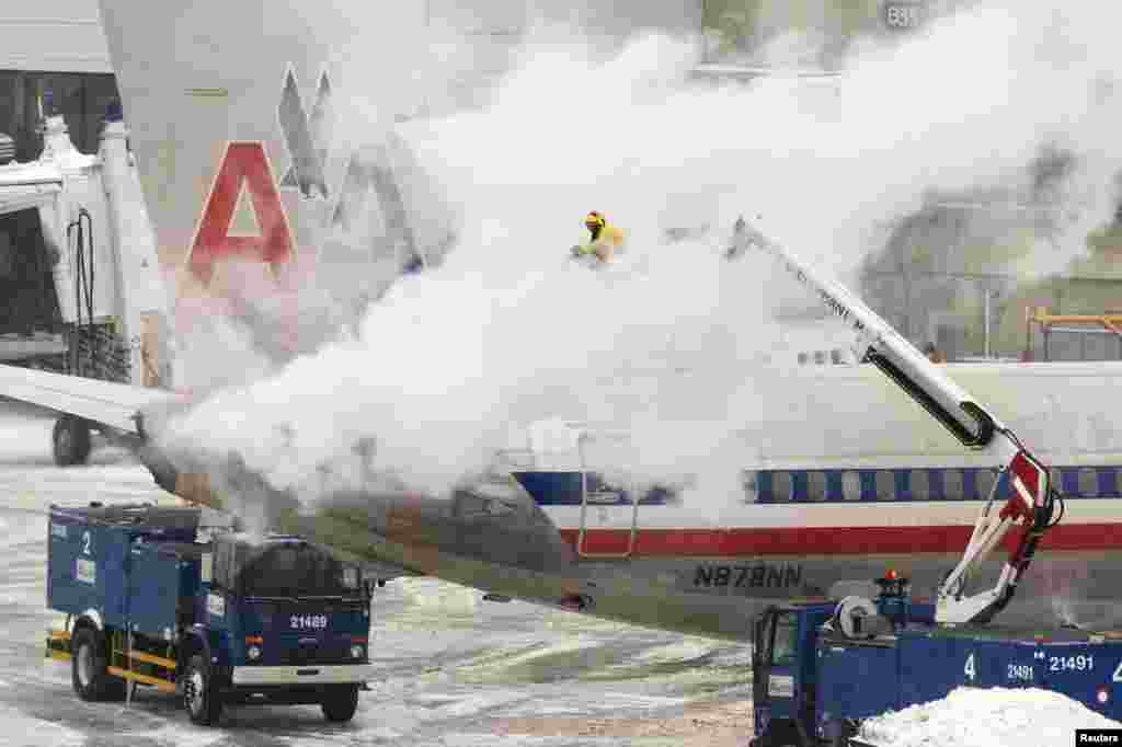 An American Airlines crew member sprays de-icing solution on a plane in Boston, Jan. 2, 2014.