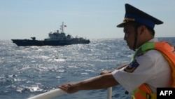 Petugas penjaga wilayah perbatasan Vietnam tampak mengamati kapal patroli perbatasan Vietnam yang berlayar di area dekat kilang minyak China di Laut China Selatan pada 14 Mei 2014. Laut China Selatan menjadi sengketa antara China dan negara-negara Asia Tenggara. (Foto: AFP)