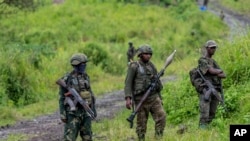 Waasi wa M23 wakisimama na silaha zao wakati wa hafla ya kuanza kuondoka katika maeneo wanayodhibiti katika mji wa Kibumba, mashariki mwa DRC, Disemba 23, 2022.