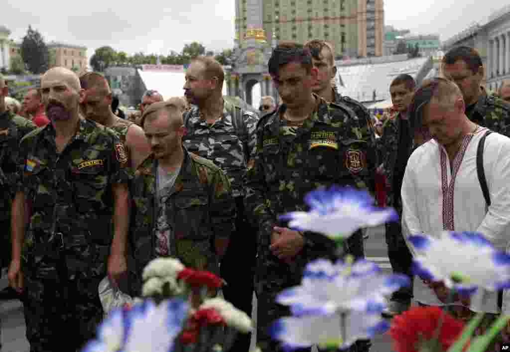Para anggota unit pertahanan diri mengheningkan cipta untuk menghormati para korban tewas di Alun-alun Independen dalam bentrokan 18-21 Februari di Kyiv dan tentara yang tewas dalam kampanye anti-teroris di Ukraina timur, di Alun-alun Independen, Kyiv (2/6). (AP/Sergei Chuzavkov)