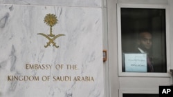 FILE - An embassy staffer peers through a glass door at an entrance of the Saudi Arabian embassy in Washington, DC.