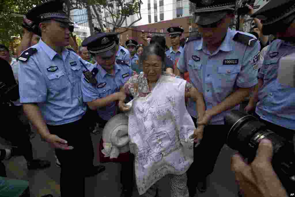 2013年8月21日，中国警察试图把一名在济南中级法院附近喊冤的老年妇女带离现场。