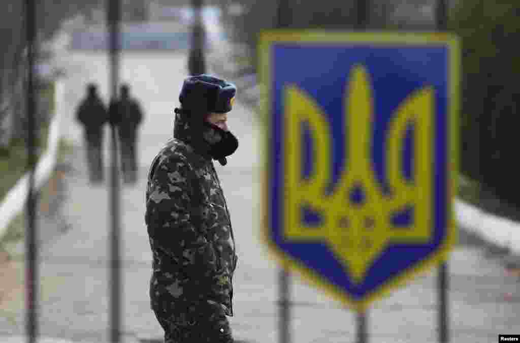 A Ukrainian soldier walks near a closed entrance gate at an airforce base in the Crimean town of Belbek, March 20, 2014.
