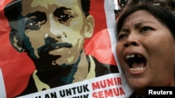 In this undated file photo, a protester holds a poster of Munir Said Thalib during a demonstration outside the National Intelligence Agency (BIN) office in Jakarta.