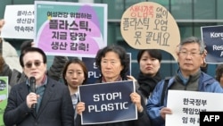 2019 年 11 月 25 日，在釜山联合国塑料污染政府间谈判委员会第五届会议 (INC-5) 举办场外，一名活动人士与其他抗议者一起举着“停止塑料”的标语。
