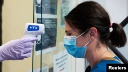Jillian Golder, an employee of Oro Valley Hospital, has her temperature checked before receiving an antibody test for the coronavirus disease (COVID-19) at the University of Arizona in Tucson, Arizona, U.S., July 10, 2020. REUTERS/Cheney Orr