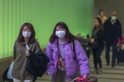Travelers arrive at LAX Tom Bradley International Terminal wearing medical masks for protection against the novel coronavirus outbreak, Feb. 2, 2020, in Los Angeles.