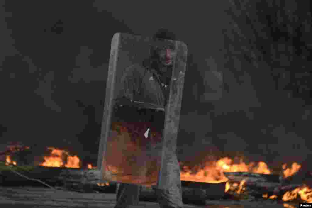 A pro-Russian protester holds a shield at a check point, while black smoke from burning tires engulfs the area, in Slovyansk, April 13, 2014.