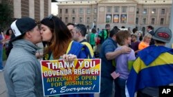 With the Arizona Capitol in the background, gay rights supporters Rachel Butas, right, and Jo Jo Halko kiss after the two learn that Arizona Gov. Jan Brewer announces she has vetoed SB1062, Feb. 26, 2014.