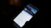 FILE - A man views Cambodian Prime Minister Hun Sen's Facebook page on his mobile phone at a side walk in downtown Phnom Penh, Cambodia.