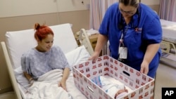 Infant Sleep Recommendations: FILE - In this May 6, 2016, file photo, Keyshla Rivera smiles at her newborn son Jesus as registered nurse Christine Weick demonstrates a baby box before her discharge from Temple University Hospital in Philadelphia on Friday, May 6, 2016.