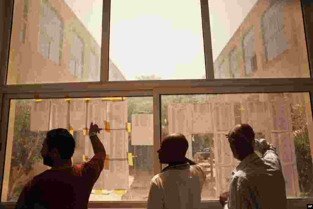 Libyan men look for their names on a voters list at a polling station in Tripoli, Libya, Saturday, July 7, 2012.