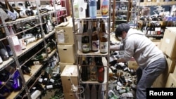 A worker cleans up broken bottles at a liquor shop after a strong quake in Fukushima, Japan, Feb. 13, 2021, in this photo taken by Kyodo.