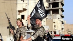 Anggota grup militan ISIL/ISIS di sepanjang jalan provinsi Raqqa, Syria bagian utara, 30 Juni 2014. (REUTERS/Stringer)