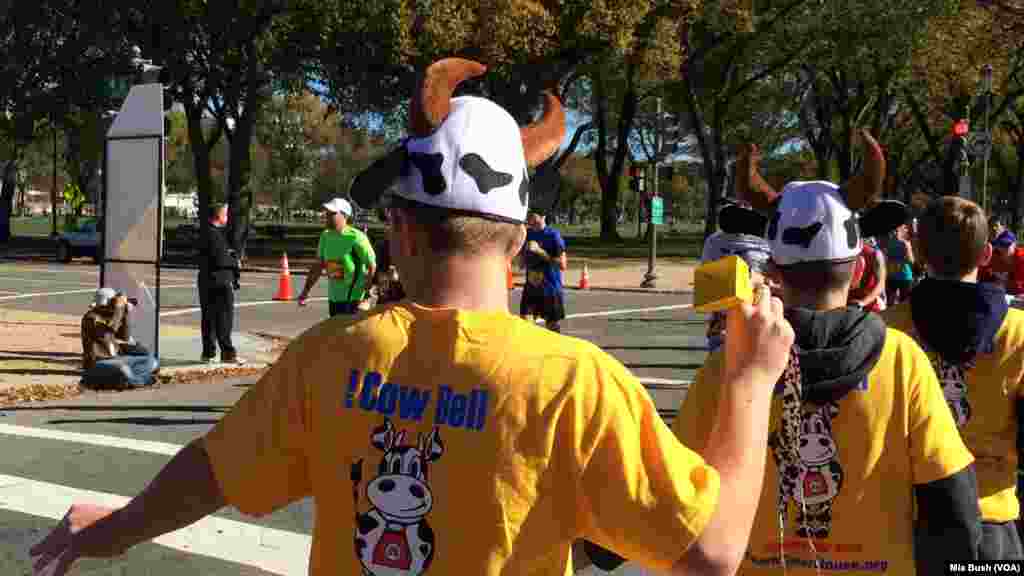 Teens wearing cow-horn hats and ringing cow bells cheer on runners in the Marine Corps Marathon along Independence Avenue Sunday.