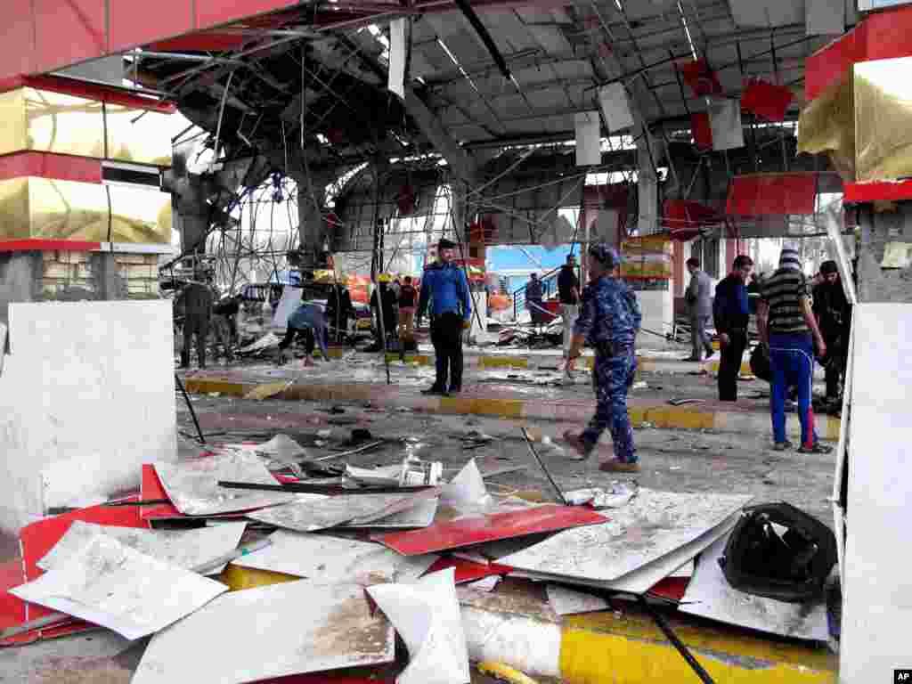 Security forces and civilians inspect the site of a massive bomb attack in Hillah, about 95 kilometers south of Baghdad, Iraq, March 9, 2014. 