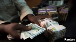 FILE - A trader changes dollars with naira at a currency exchange store in Lagos, Nigeria.