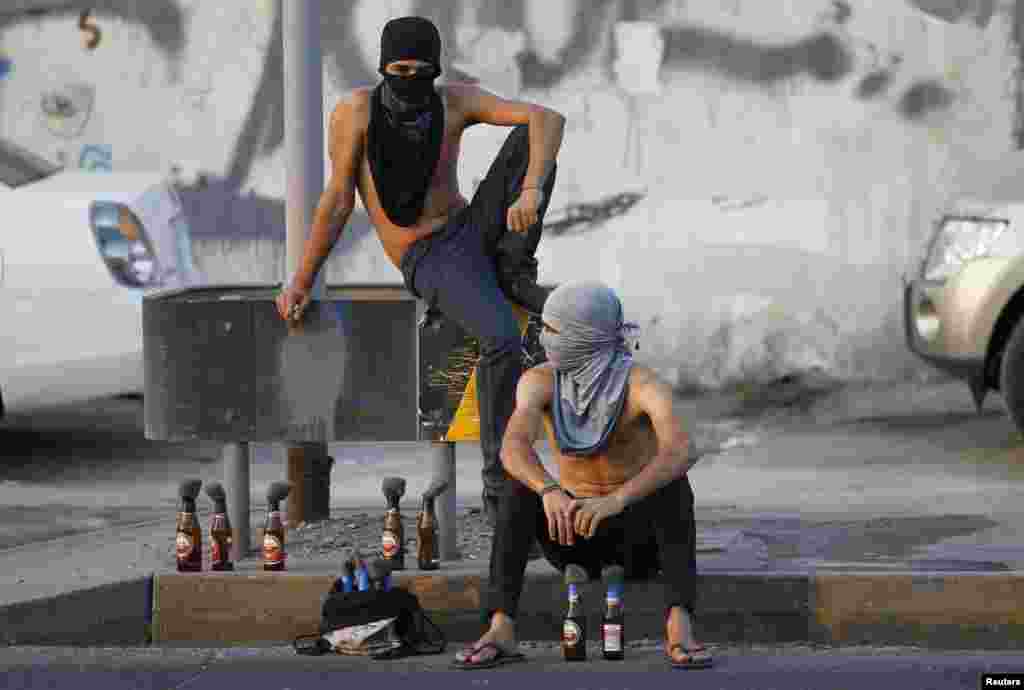Para demonstran anti-pemerintah duduk di pinggir jalan dengan bom-bom molotov sambil menunggu orang-orang lainnya untuk bergabung ketika terjadi bentrokan setelah prosesi Asyura di desa Sanabis, Manama barat, Bahrain.