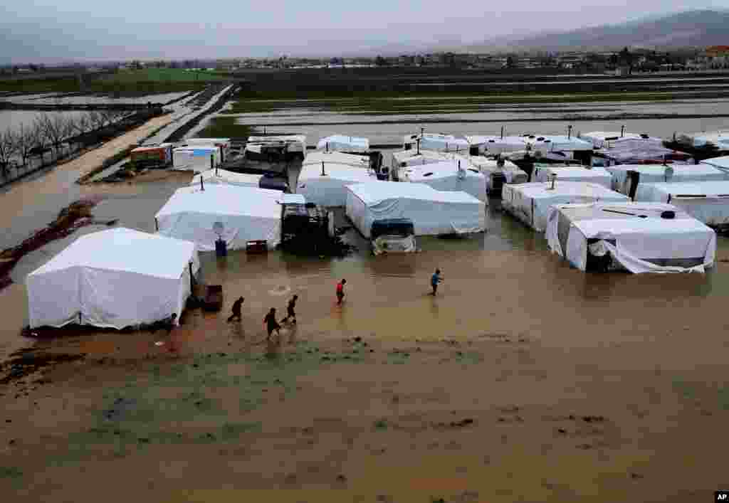 Syrian refugees make their way in flooded water at a temporary refugee camp, in the eastern Lebanese Town of Al-Faour near the border with Syria, January 8, 2013.