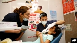 FILE - UT Health Dental School student volunteers provide a free dental screening on a child at Fiesta Mart in Houston, June 13, 2015.