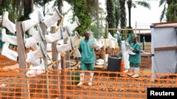 Congolese health workers clean gumboots as they prepare the Ebola treatment center in the village of Mangina in North Kivu province of the Democratic Republic of Congo, Aug. 18, 2018.
