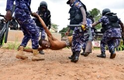 Ugandan riot policemen detain a supporter of presidential candidate Robert Kyagulanyi, also known as Bobi Wine, in Luuka district, eastern Uganda, Nov. 18, 2020.