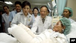 Thailand's Prime Minister Yingluck Shinawatra, third left, visits a victim of Saturday's car bomb attacks at a hospital in Hat Yai Songkhla province, southern Thailand, April 2, 2012.