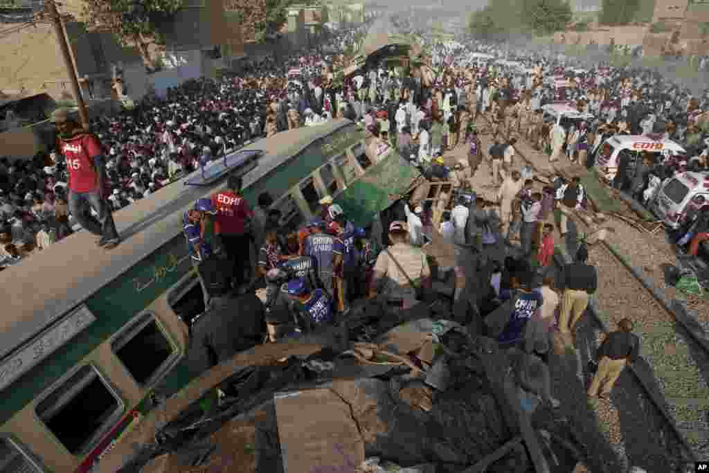 Warga mencari para korban di antara rongsokan gerbong kereta api dalam tabrakan kereta di Karachi, Pakistan yang menewaskan sedikitnya 21 orang.